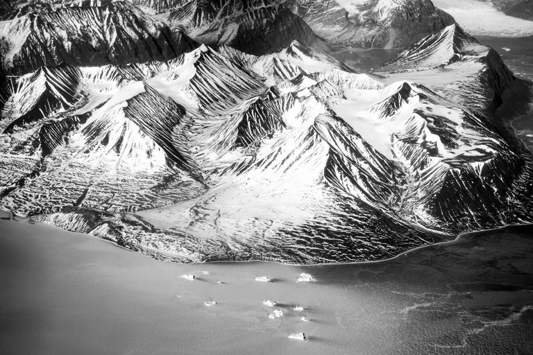 Aerial black and white view of icy landscape and coast