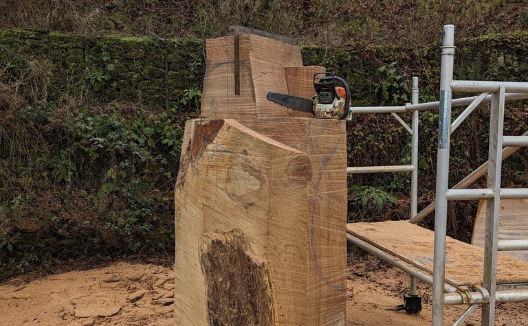 A timber block in a work yard with scaffolding and chainsaw in view