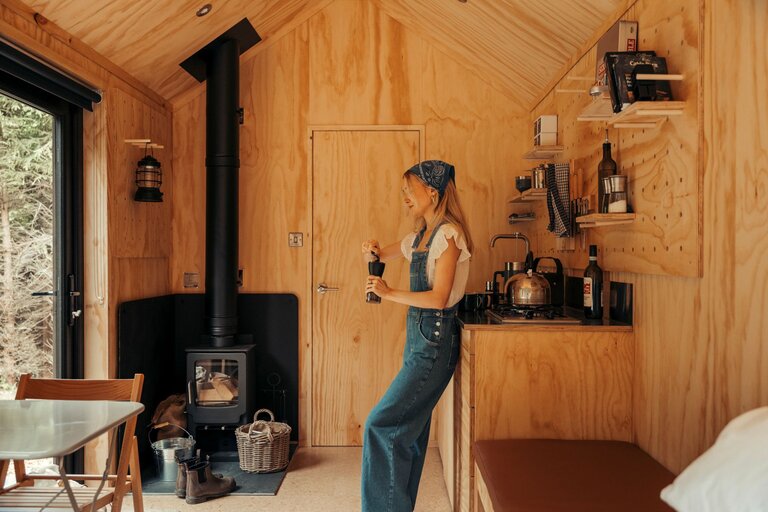 A woman griding coffee inside a cabin
