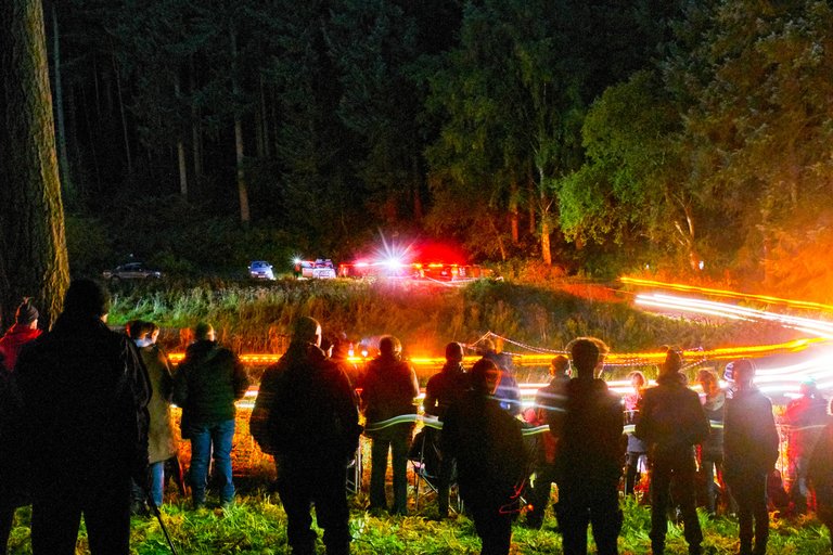 A blur of lights beyond a group of spectators at night rally