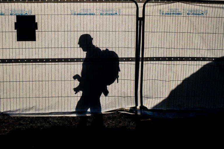 Silhouette of camera man waiting to take photos by metal fencing 