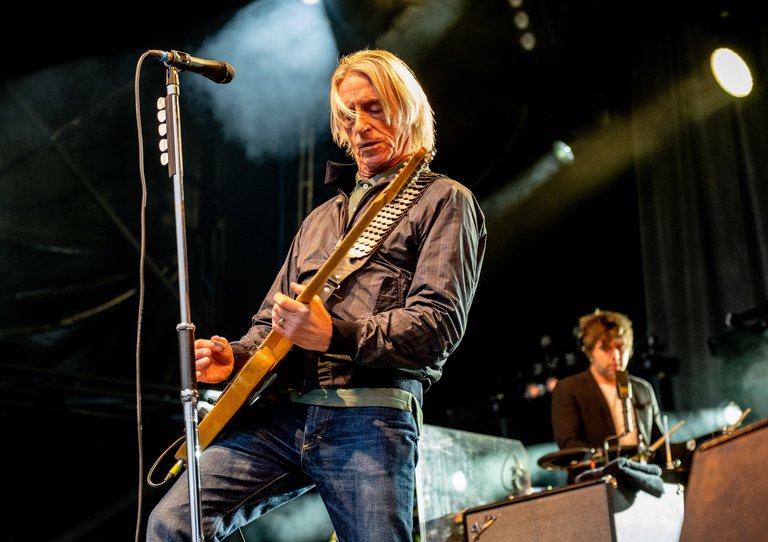 Paul Weller strumming guitar on stage at Forest Live event